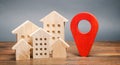 Miniature wooden houses and a geolocation marker. Location of residential buildings. City orientation. Checking the location of a