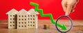 Miniature wooden houses and a green arrow down. The concept of low cost real estate. Lower mortgage interest rates. Falling prices Royalty Free Stock Photo