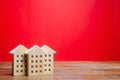 Miniature wooden houses on a red background. Real estate concept. City. Agglomeration and urbanization. Market Analytics. Demand