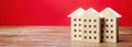 Miniature wooden houses on a red background. Real estate concept. City. Agglomeration and urbanization. Market Analytics. Demand