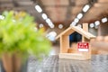 Miniature wooden houses with For Sale sticker and blur green plants in the foreground. Buying the first dream house. Royalty Free Stock Photo