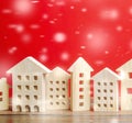 Miniature wooden houses and snowflakes on a red background. Christmas discounts and real estate sales. New Year or Xmas winter Royalty Free Stock Photo