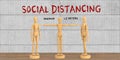 Miniature wooden mannequins with the message SOCIAL DISTANCING