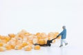 Miniature worker carrying giant corn kernels with a cart