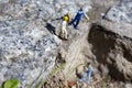 Miniature worker carrying a sand bag on a construction site while an instructor giving orders