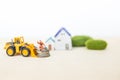 Miniature worker on coin stack with front loader truck over blurred house background, property investment Royalty Free Stock Photo