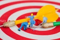 Miniature worker toy on red dart board with green dart Royalty Free Stock Photo