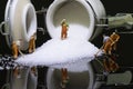 Miniature workers are cleaning up the sugar that has fallen from the white ceramic jar Royalty Free Stock Photo