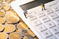 Miniature workers digging tax button on calculator on pile of coins Royalty Free Stock Photo