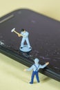 Miniature Workers recycling a broken cell phone Royalty Free Stock Photo