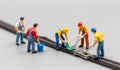 Miniature workers repair model train tracks in a detailed scene of teamwork and precision Royalty Free Stock Photo