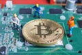 Miniature working man digging and mining Bitcoin on printed circuit board