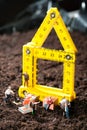 Miniature workmen building a house