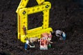 Miniature workmen building a house