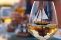 miniature yacht in a glass of chardonnay, person in the background clinking glasses Royalty Free Stock Photo