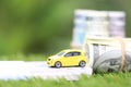 Miniature yellow car model with dollas banknotes on nature green background, Saving money for car, Finance and car loan,