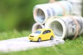 Miniature yellow car model with dollas banknotes on nature green background, Saving money for car, Finance and car loan,