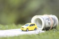 Miniature yellow car model with dollas banknotes on nature green background, Saving money for car, Finance and car loan,