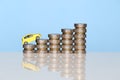 Miniature yellow car model on growing stack of coins money on blue background, Saving money for car, Finance and car loan, Royalty Free Stock Photo