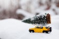 Miniature yellow car with spruce tree. Christmas theme.