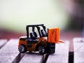 Miniature yellow forklift model on wooden table. Warehouse logistics business