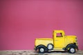 Miniature yellow toy car on wood table pink wall background. Royalty Free Stock Photo