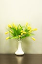 Miniature yellow tulip flowers in a white vase. Cute sunny bunch