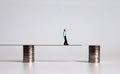 Miniature young man walking on a pile of coins.