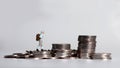 A miniature young woman walking on a pile of coins.