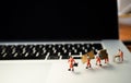 Miniatures of figurines workers moving furniture with keyboard at background