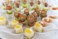 Miniburgers, canapes with pesto sauce. In the background are toasts with fried eggs, cheese and salad. Royalty Free Stock Photo