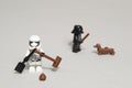 Minifigure of stormtrooper soldier cleaning dog poop while Darth Vader plays