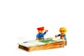 Minifigure toy worker model standing of a pilo of euro banknote, money Royalty Free Stock Photo