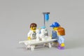 Minifigure of Veterinarian examining sick white French Poodle on a bed at the clinic with his owners watching him and concerned