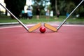 Minigolf iron rackets and a red ball at a court ground.