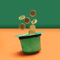 Minimal abstract magic treasure concept. Green glitter hat with golden coins levieting out of it. Green pastel and orange