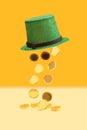 Minimal abstract magic treasure concept. Green glitter top hat with golden coins falling out of it. Yellow pastel and orange