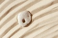 Minimal background with one stone with hole on fine sand with wave ripple. Natural happy stone light ivory color. Symbol Royalty Free Stock Photo