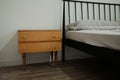 Minimal bedside area with a old retro wooden nightstand next to a bed, emphasizing simplicity, warmth, and functional interior Royalty Free Stock Photo