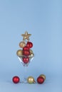 Minimal Christmas party idea. Cocktail glass with Christmas bauble balls on blue background Royalty Free Stock Photo