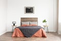 Minimal classic bedroom with wooden bed, coral linen sheets and black and white artwork