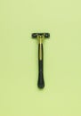The minimal composition is a black and green men`s razor on a green background. The central composition. Flat lay
