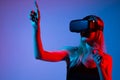 Woman Wearing VR Headset Pointing at Virtual Interface, High Tech Metaverse Experience and Future Digital Interaction Royalty Free Stock Photo