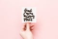 Minimal composition on a white background with girl`s hand holding card with inspirational quote find your happy place written in