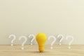 Minimal concept creative idea and innovation. Yellow light bulb revealing an idea with question symbol on a wood background. Royalty Free Stock Photo