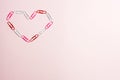 Minimal concept. Heart symbol made of stationery clips on pink background. Flat lay, top view