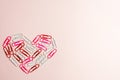 Minimal concept. Heart symbol made of stationery clips on pink background. Flat lay, top view