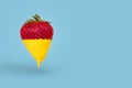 Minimal concept made with strawberry dripping with yellow paint on bright blue background