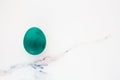 Minimal easter concept of dark green egg. Stylish Easter emerald color on white marble background. The flat lay