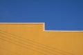 Yellow Building Wall with shadow of electric cable lines on surface against blue clear sky Royalty Free Stock Photo